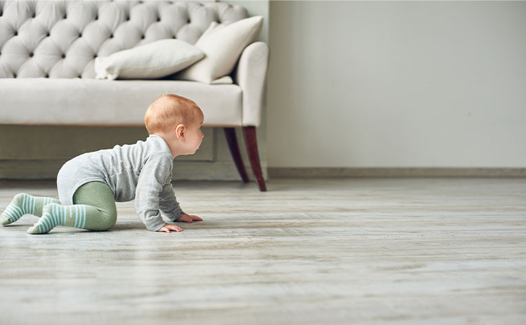 Baby crawling on wood-look flooring in living room